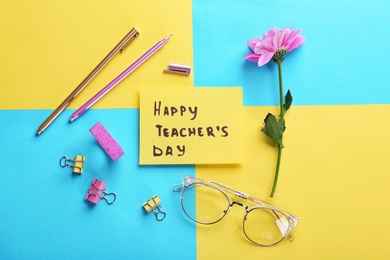 Photo of Paper with inscription HAPPY TEACHER'S DAY and stationery on color background