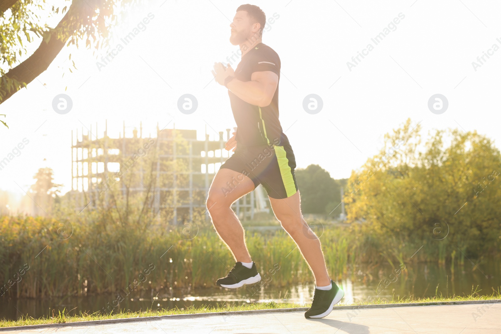 Photo of Young man running near pond in park