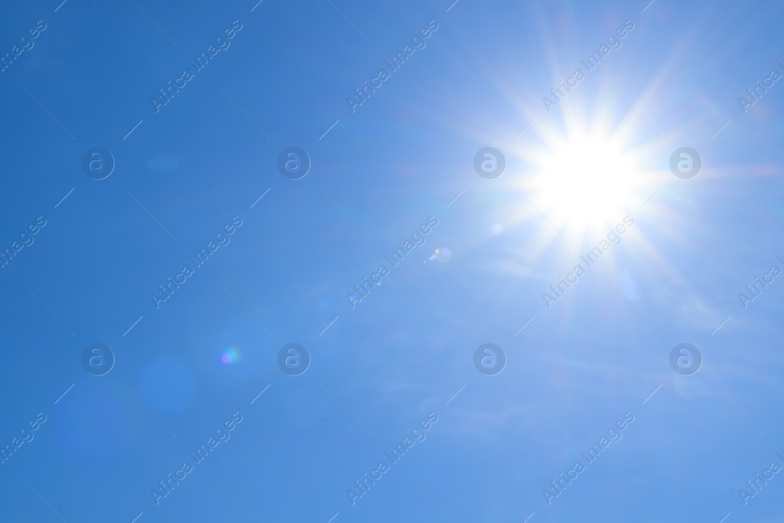 Photo of Bright sun in blue sky. Halo effect