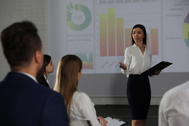 Photo of Female business trainer giving lecture in conference room with projection screen