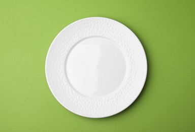 Photo of One clean plate on green background, top view