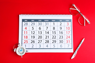 Photo of Calendar, glasses and alarm clock on red background, flat lay