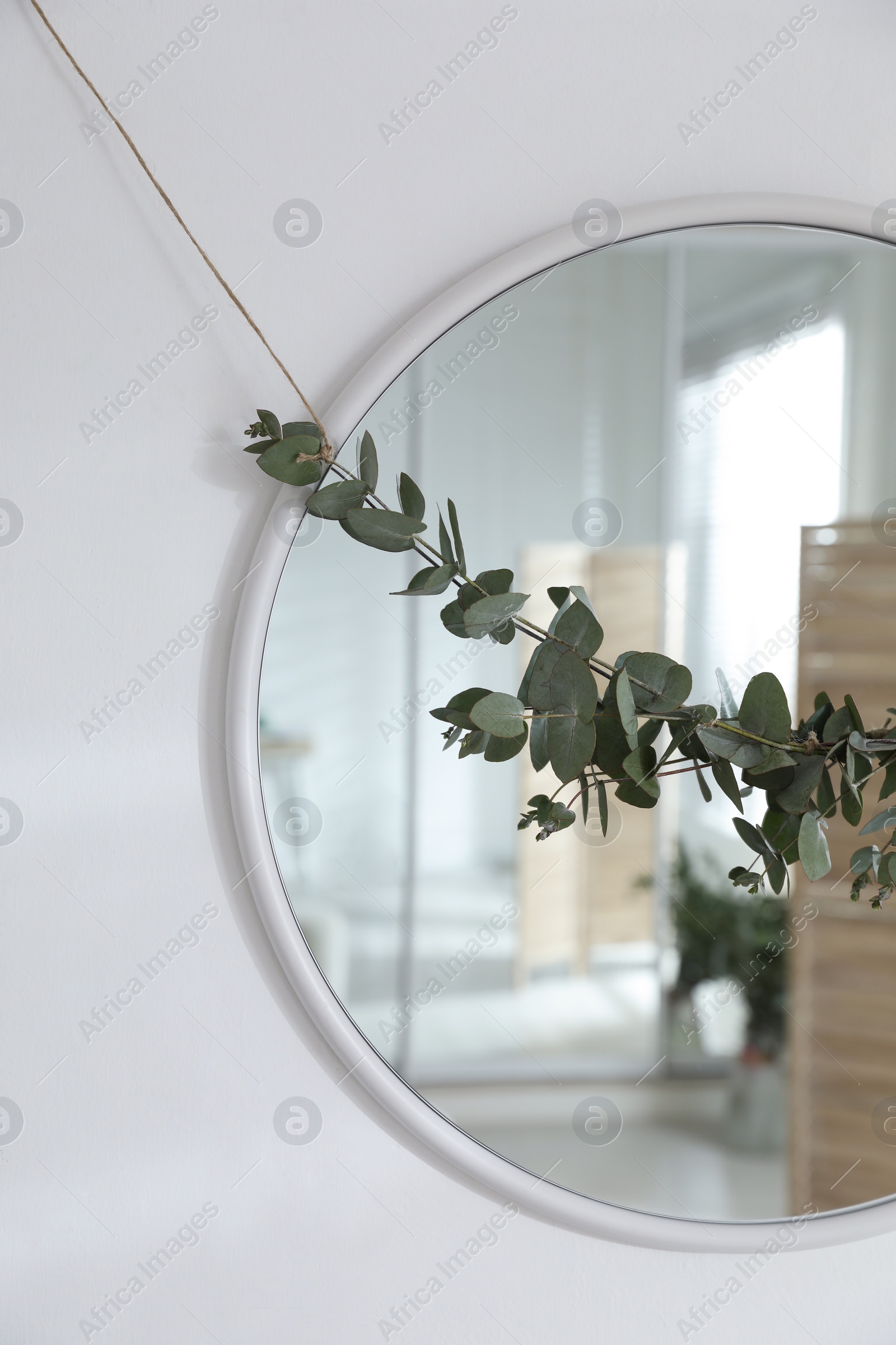 Photo of Stylish mirror decorated with beautiful eucalyptus garland on white wall