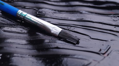 Brush on artist's palette with black paint, closeup