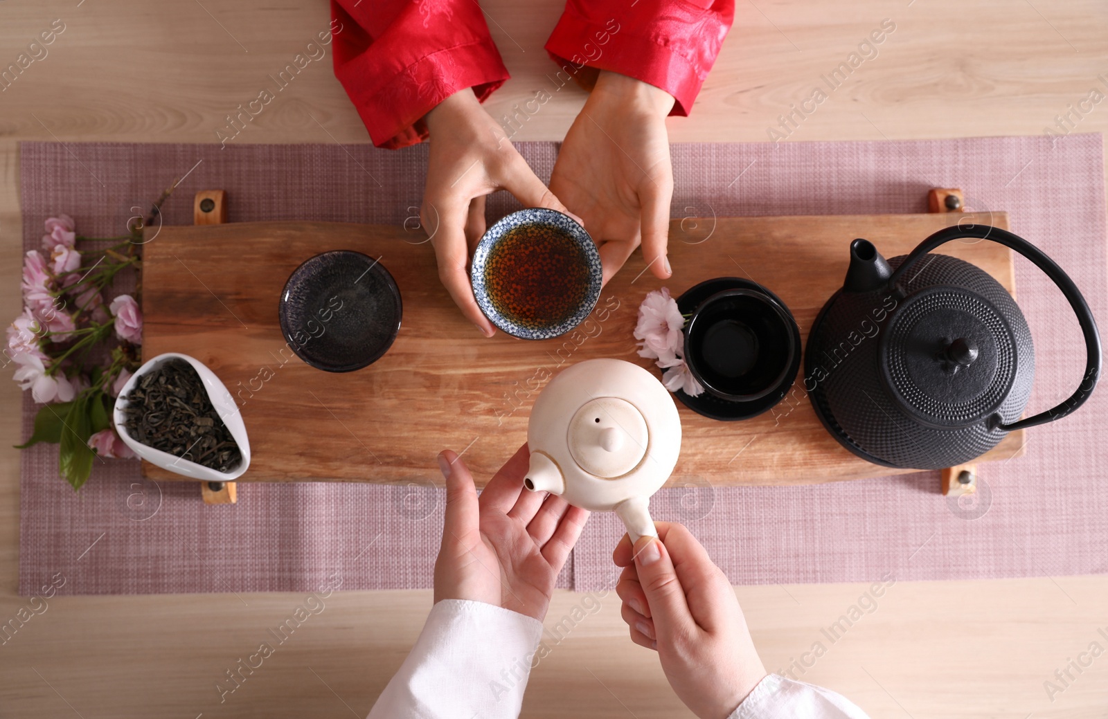 Photo of Master and guest tea during traditional ceremony at wooden table, top view
