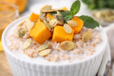 Photo of Tasty wheat porridge with pumpkin and mint in bowl, closeup