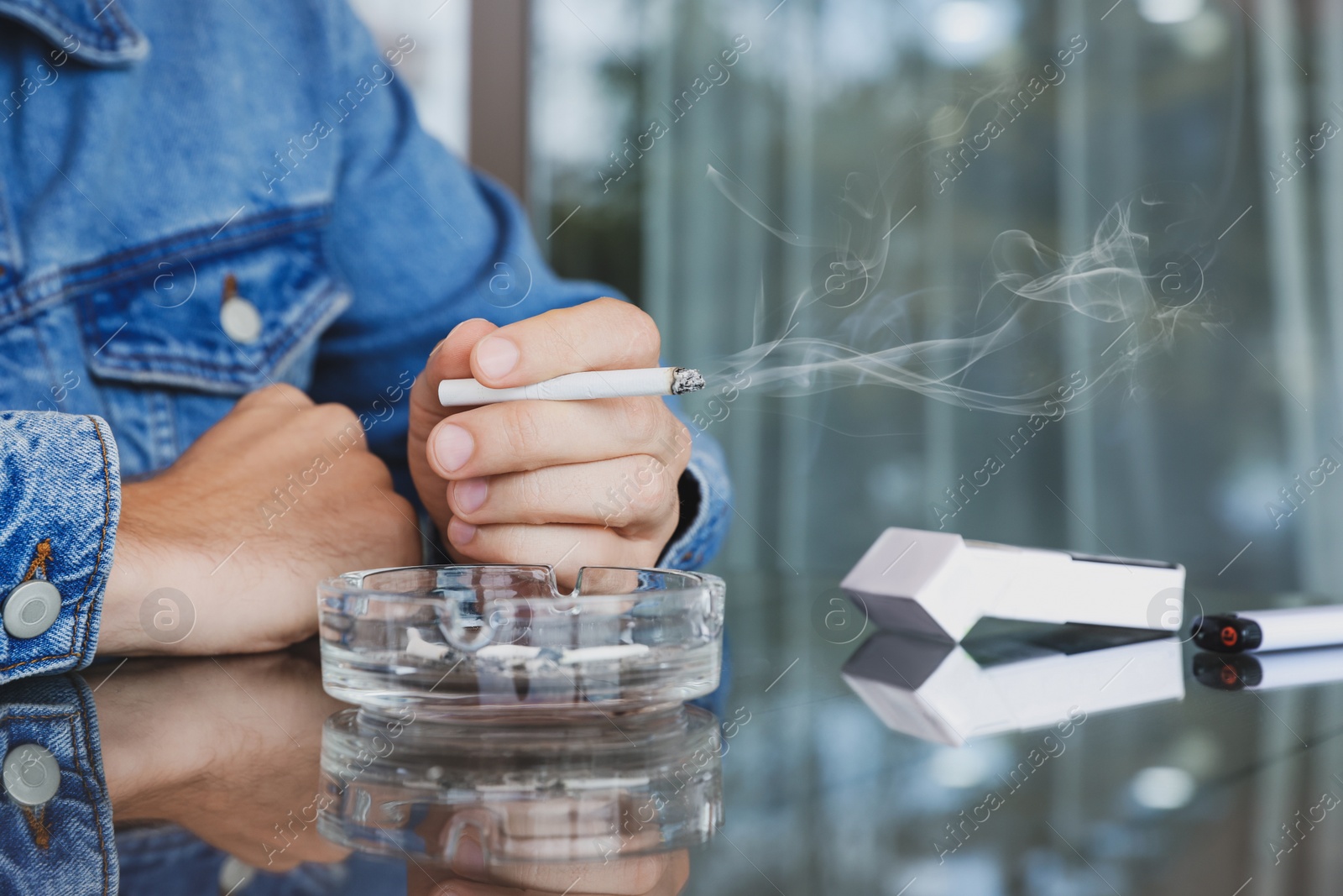 Photo of Man smoking cigarette at table in outdoor cafe, closeup