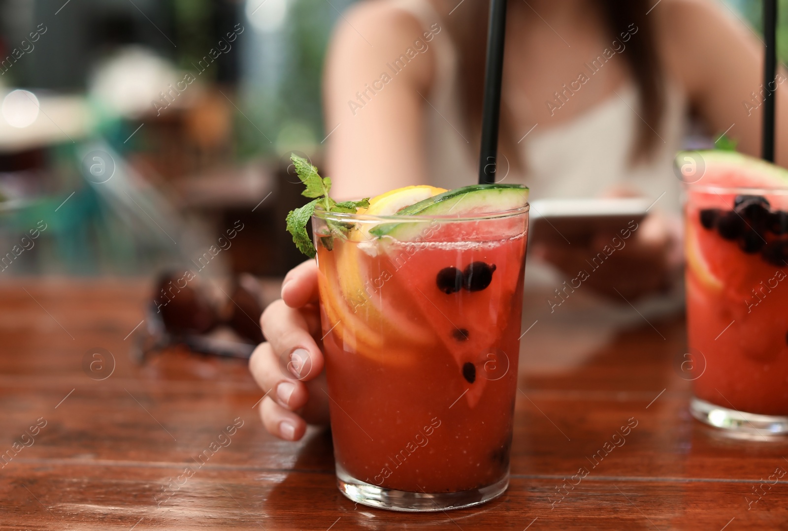 Photo of Woman with glass of tasty lemonade at table, closeup