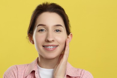 Photo of Portrait of smiling woman with dental braces on yellow background