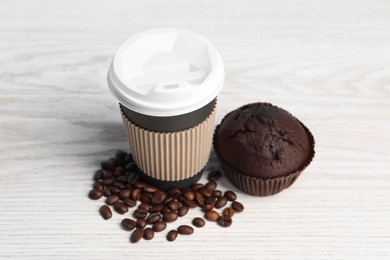 Photo of Paper cup with plastic lid, muffin and coffee beans on white wooden table. Coffee to go