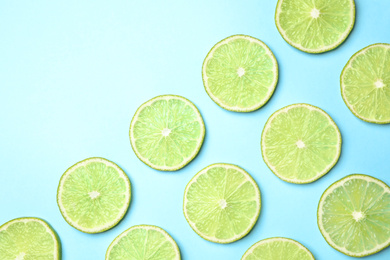 Photo of Fresh juicy lime slices on light blue background, flat lay