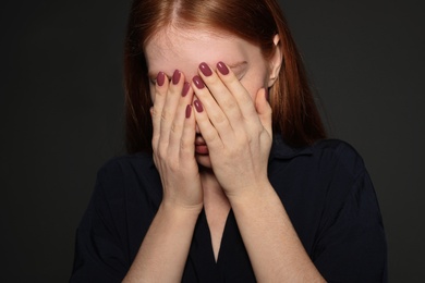 Photo of Upset young woman crying against dark background