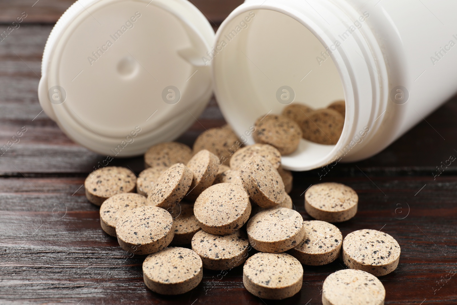 Photo of Bottle and vitamin pills on wooden table, closeup