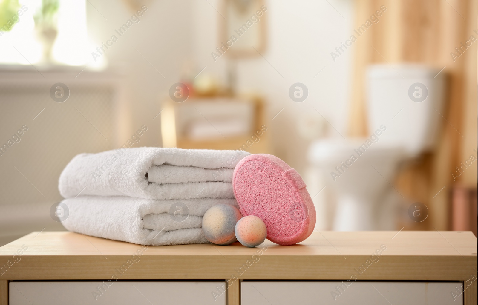 Photo of Clean towels and toiletries on table against blurred background