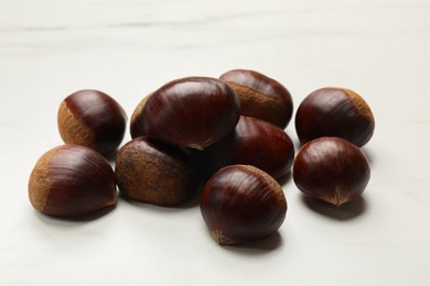 Photo of Sweet fresh edible chestnuts on white table, closeup