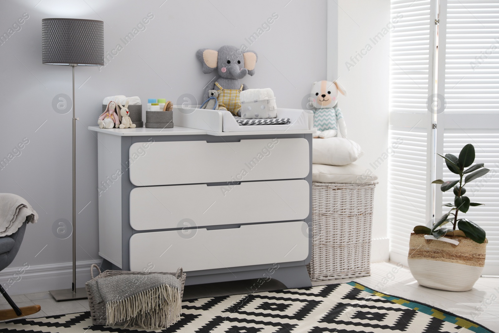 Photo of Changing tray and pad on chest of drawers in baby room. Interior design