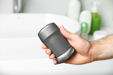 Photo of Man holding stick deodorant in bathroom, closeup view