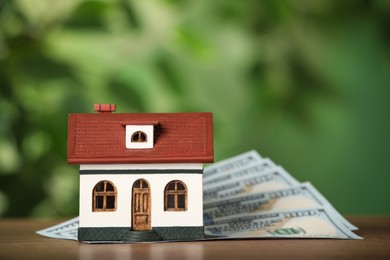 Photo of Mortgage concept. House model and money on wooden table against blurred background