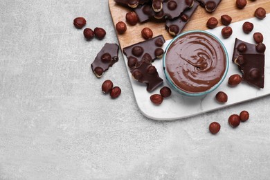 Photo of Bowl with tasty paste, chocolate pieces and nuts on light grey table, flat lay. Space for text