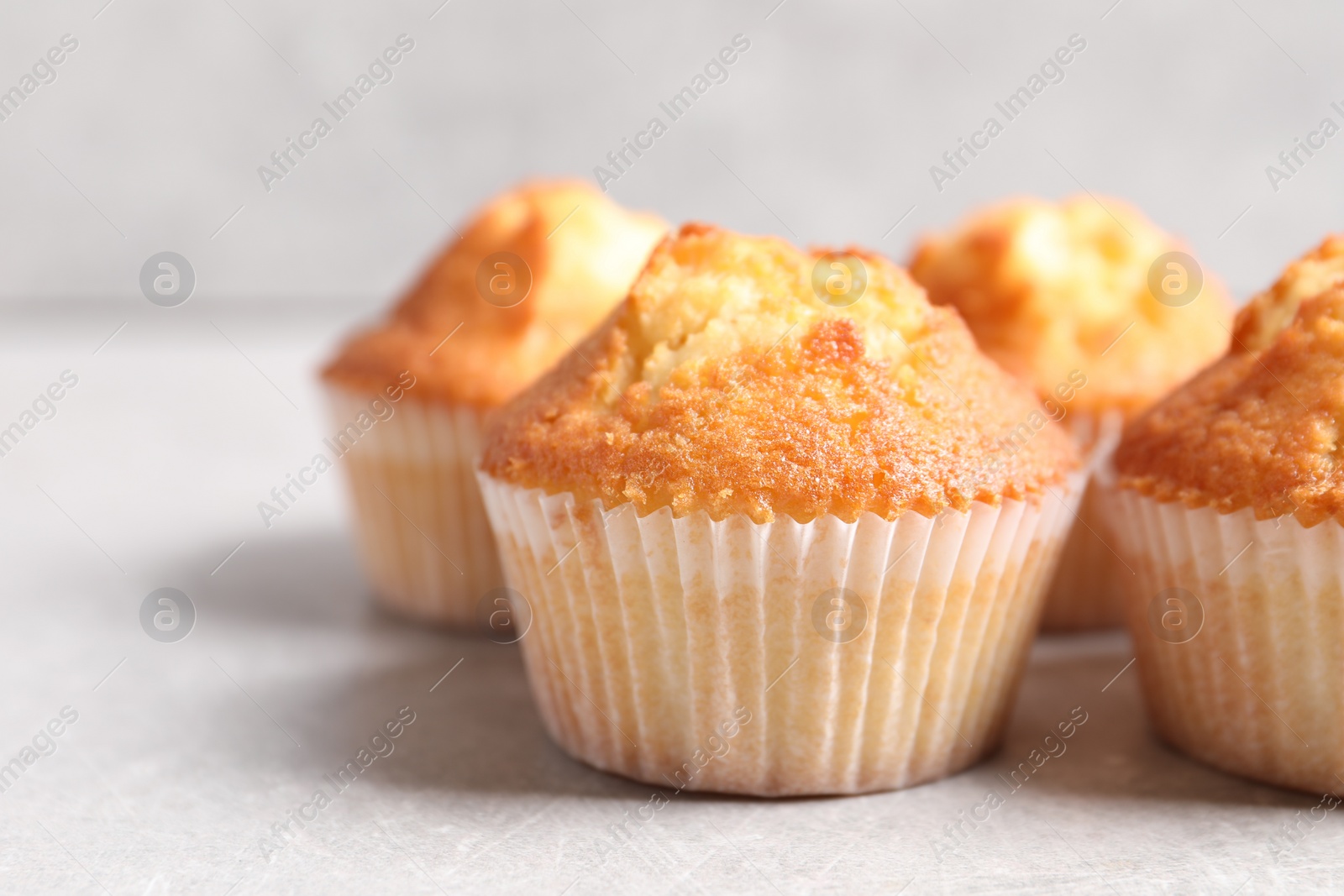 Photo of Tasty muffins on light grey table, closeup. Space for text