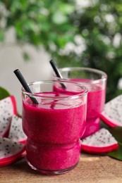 Photo of Delicious pitahaya smoothie and fresh fruits on wooden table