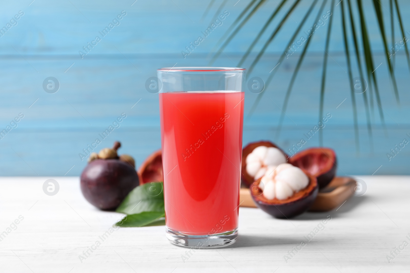 Photo of Delicious fresh mangosteen juice in glass on white table