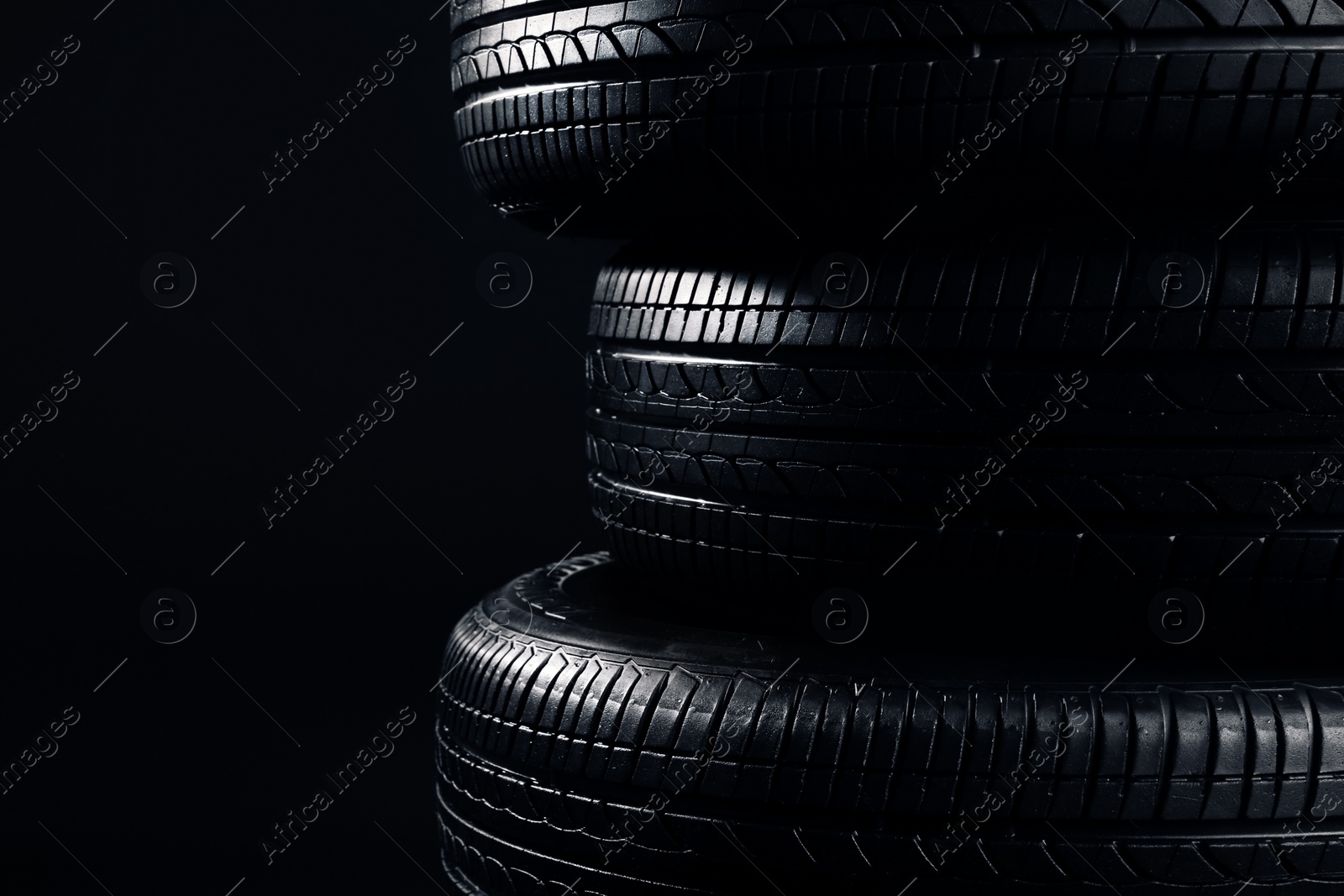 Photo of Stack of car tires on black background, closeup