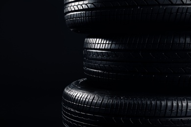 Stack of car tires on black background, closeup