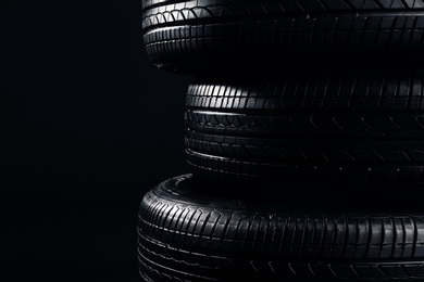 Photo of Stack of car tires on black background, closeup