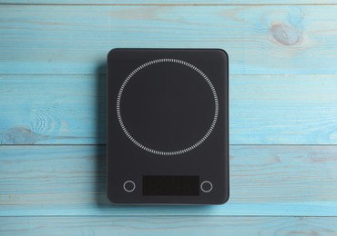 Photo of Modern digital kitchen scale on light blue wooden table, top view