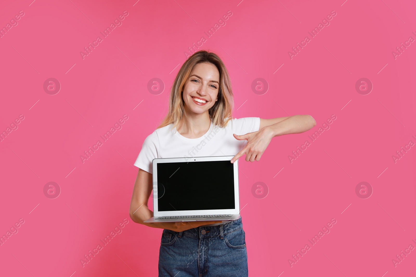 Photo of Young woman with modern laptop on pink background