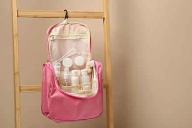 Photo of Cosmetic travel kit in compact toiletry bag against beige wall, space for text. Bath accessories