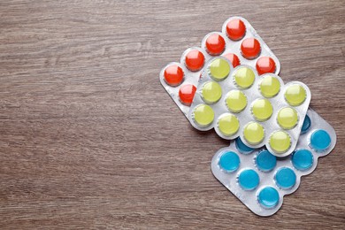 Photo of Blisters with colorful cough drops on wooden background, flat lay. Space for text