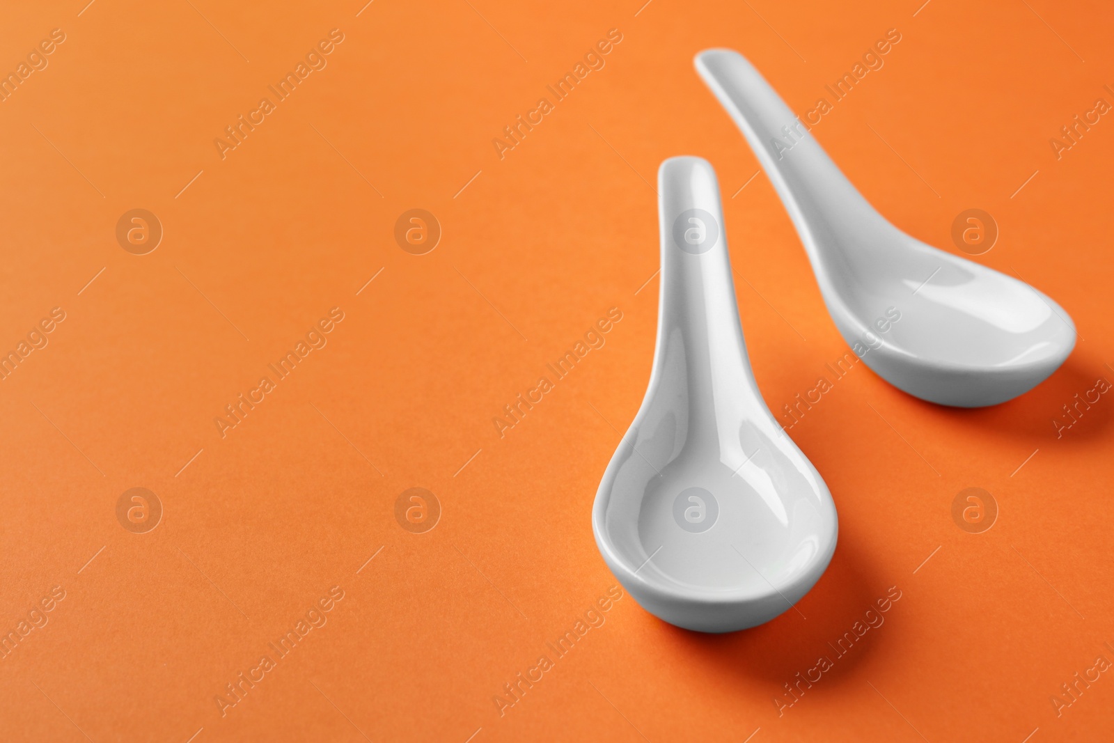 Photo of Miso soup spoons on orange background. Space for text