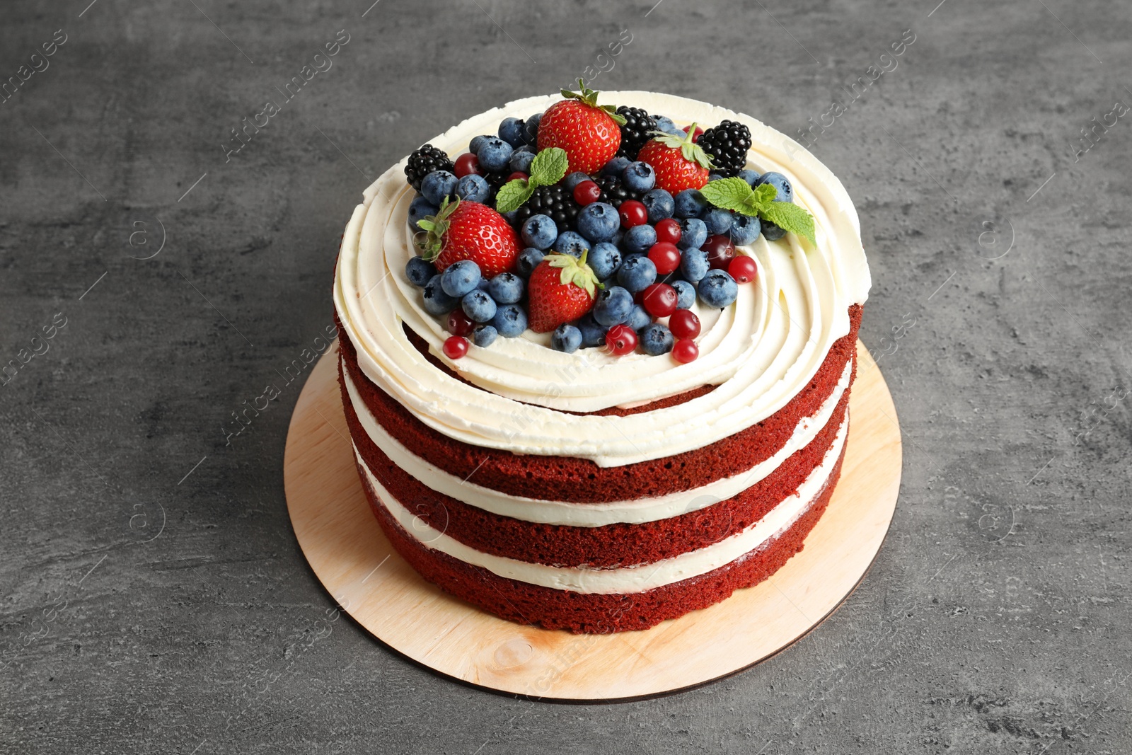 Photo of Delicious homemade red velvet cake with fresh berries on table