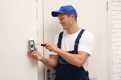 Male technician installing fingerprint security alarm system indoors