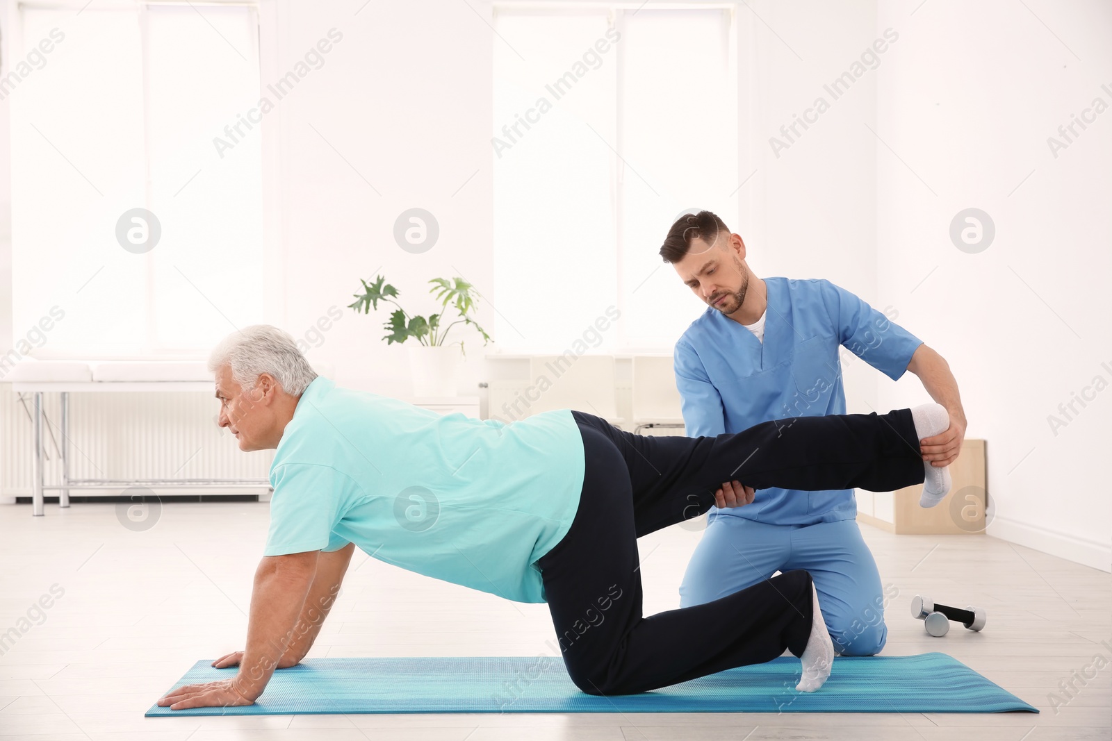 Photo of Young physiotherapist working with senior patient in clinic