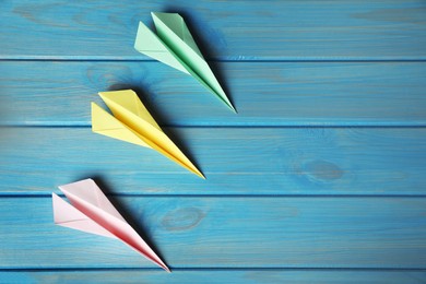 Photo of Handmade paper planes on light blue wooden table, flat lay. Space for text