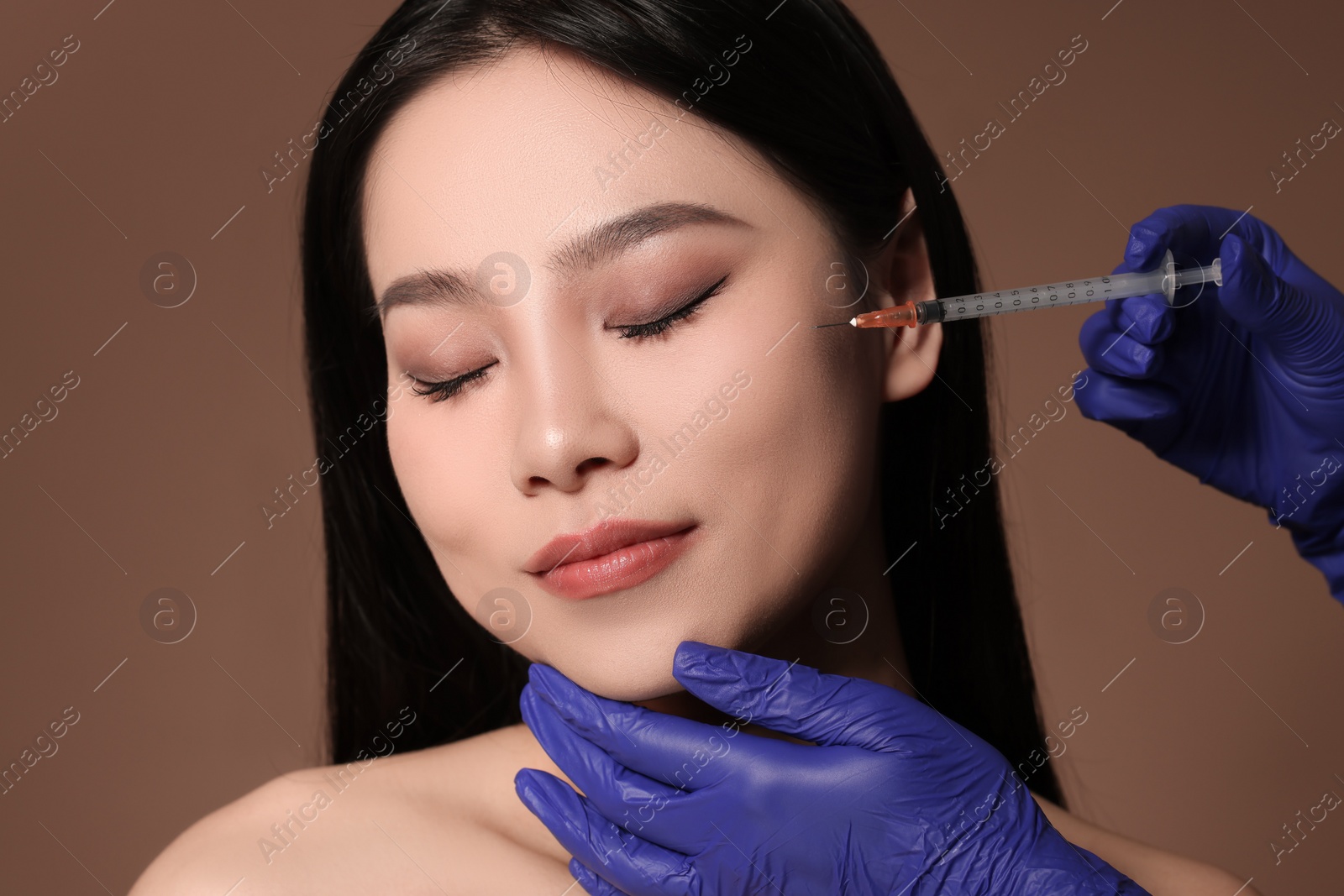 Photo of Woman getting facial injection on brown background