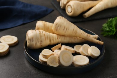 Photo of Whole and cut parsnips on black table