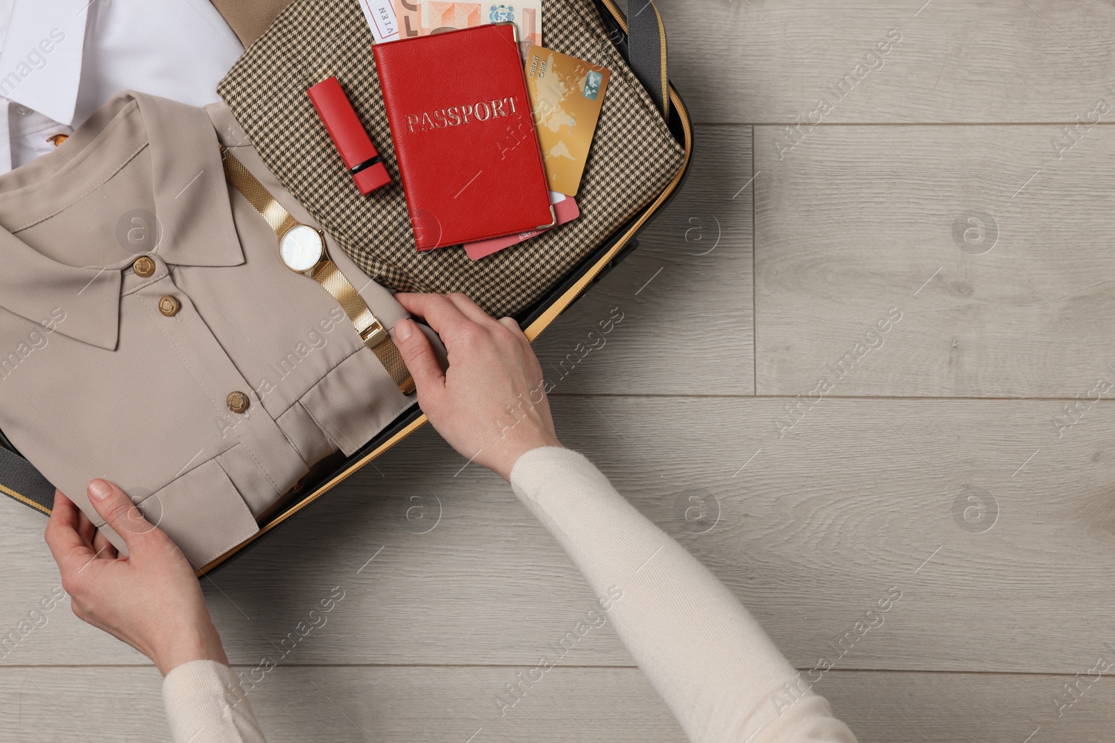 Photo of Woman packing suitcase on wooden floor, top view with space for text. Business trip planning