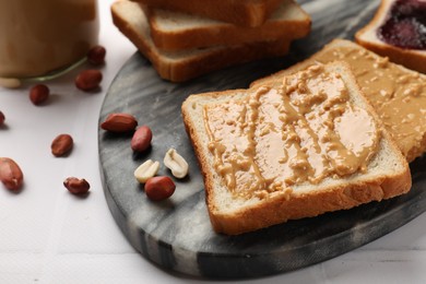 Photo of Delicious toasts with peanut butter and nuts on white table, closeup