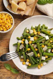 Photo of Delicious salad with green beans, corn and cheese served on wooden table, flat lay