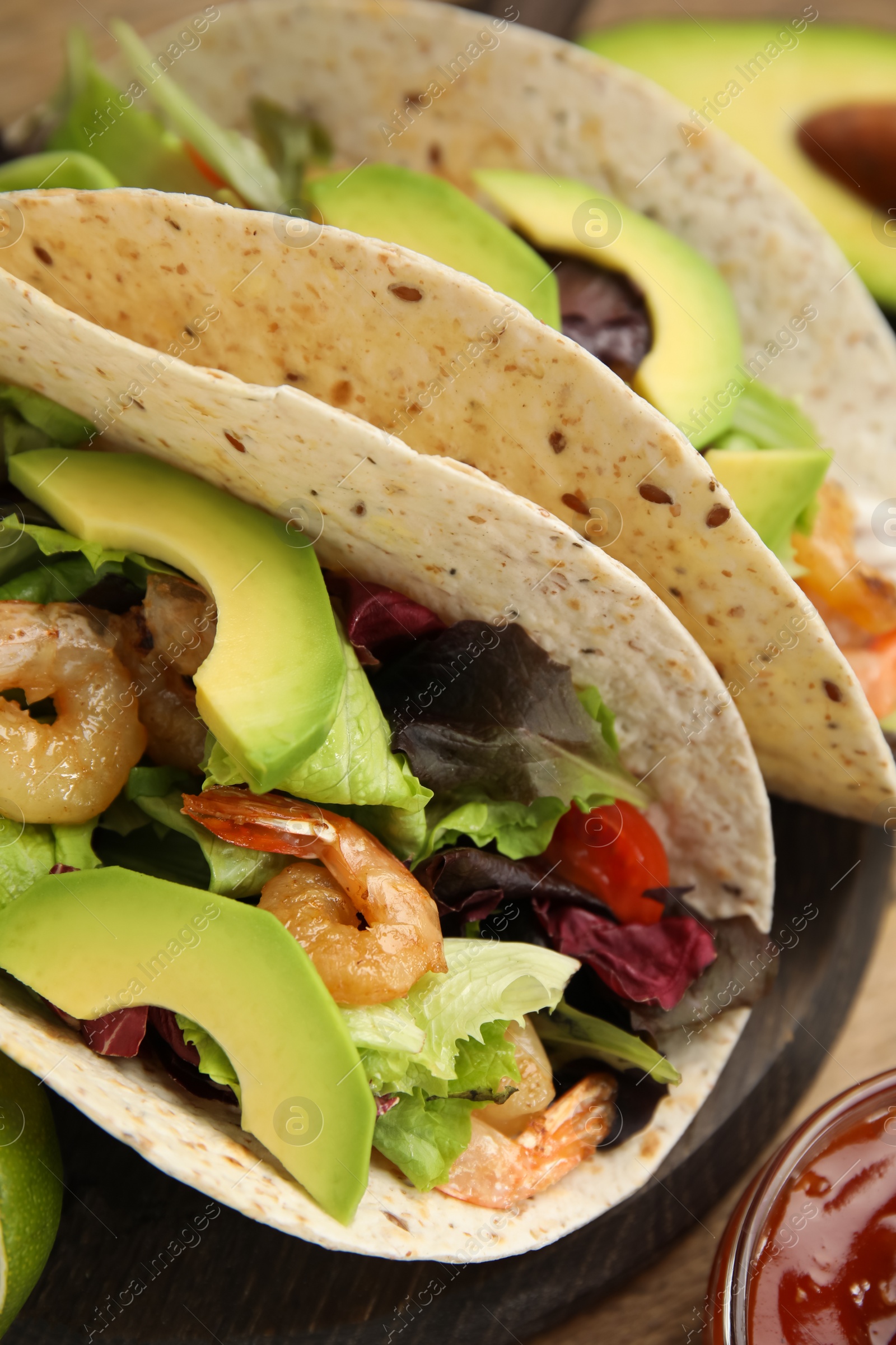 Photo of Delicious tacos with shrimps and avocado on table, closeup