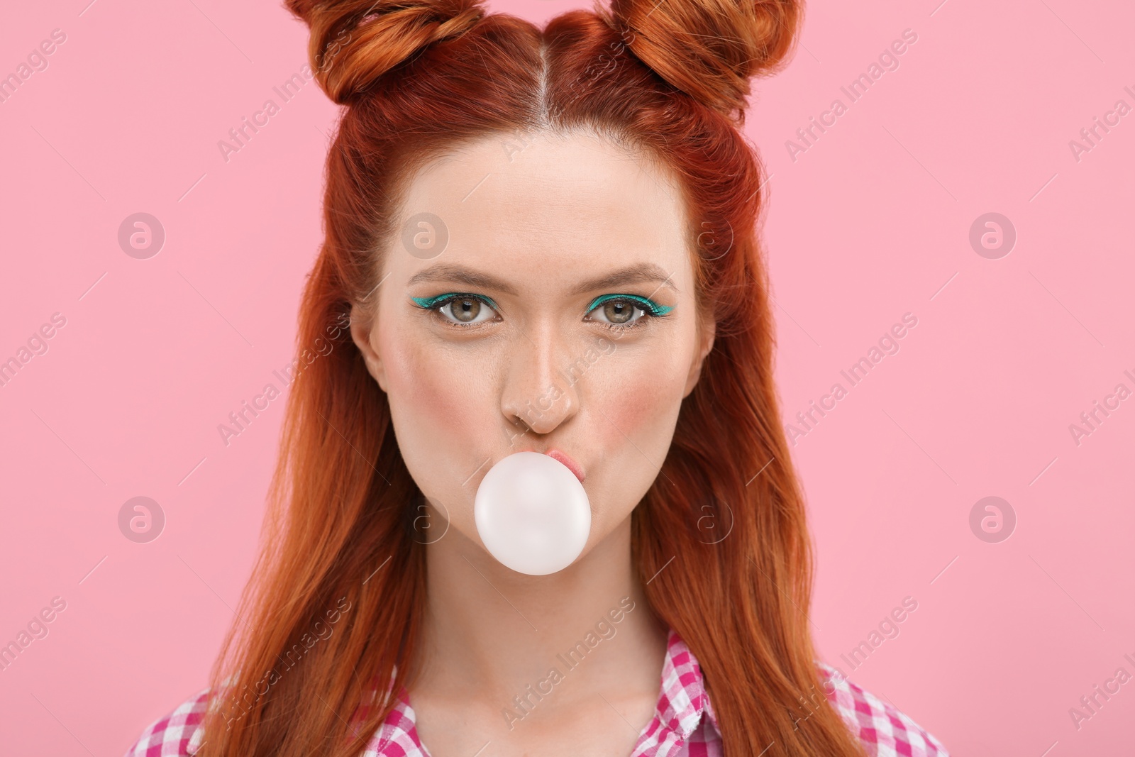 Photo of Portrait of beautiful woman with bright makeup blowing bubble gum on pink background