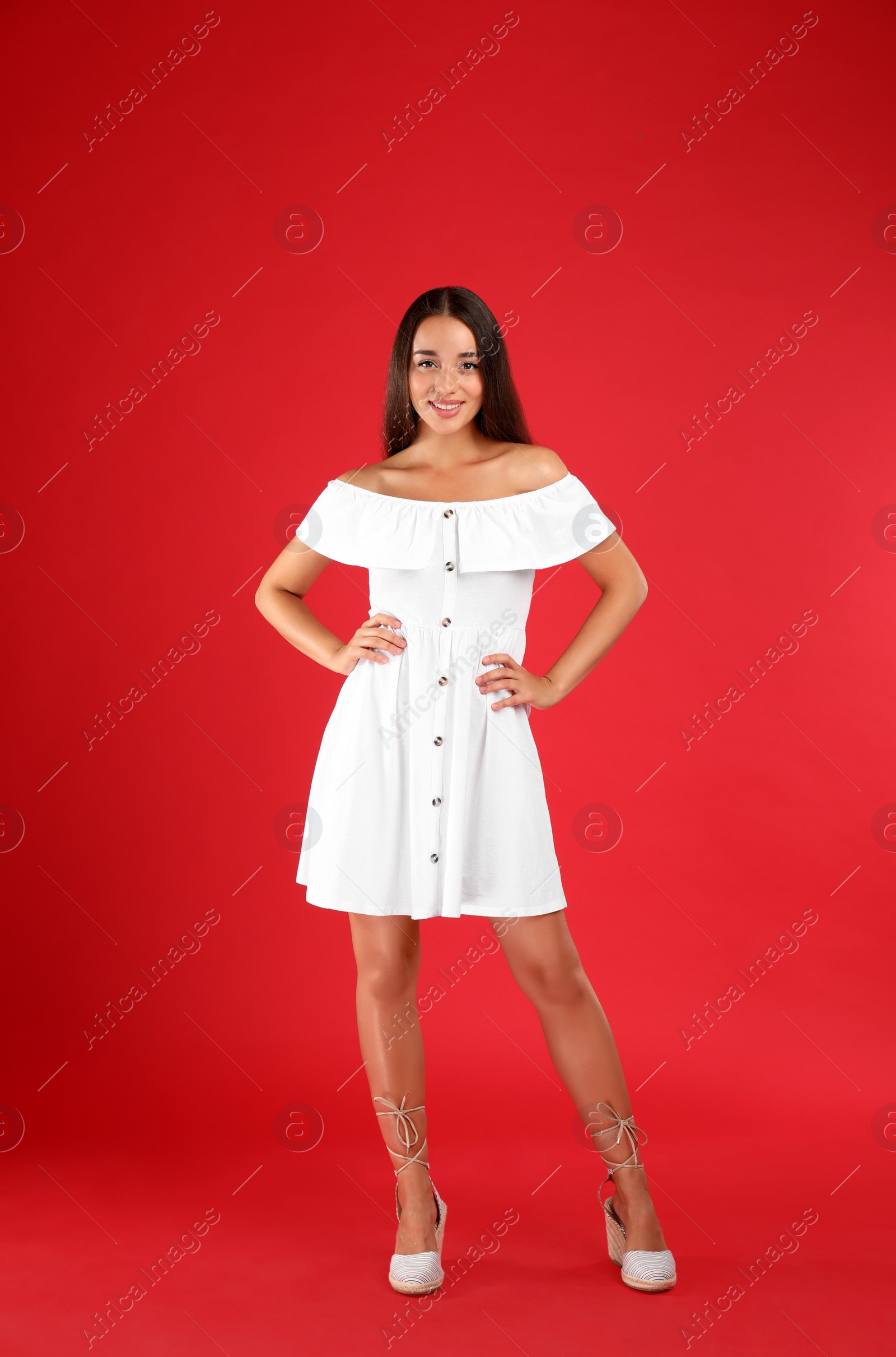 Photo of Young woman wearing stylish white dress on red background