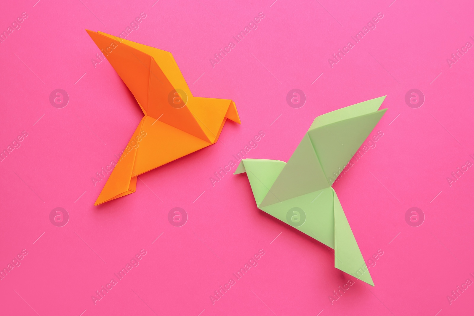 Photo of Beautiful colorful origami birds on pink background, flat lay