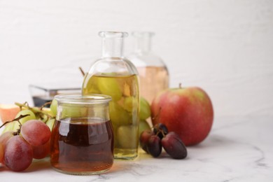 Photo of Different types of vinegar and ingredients on light marble table, closeup