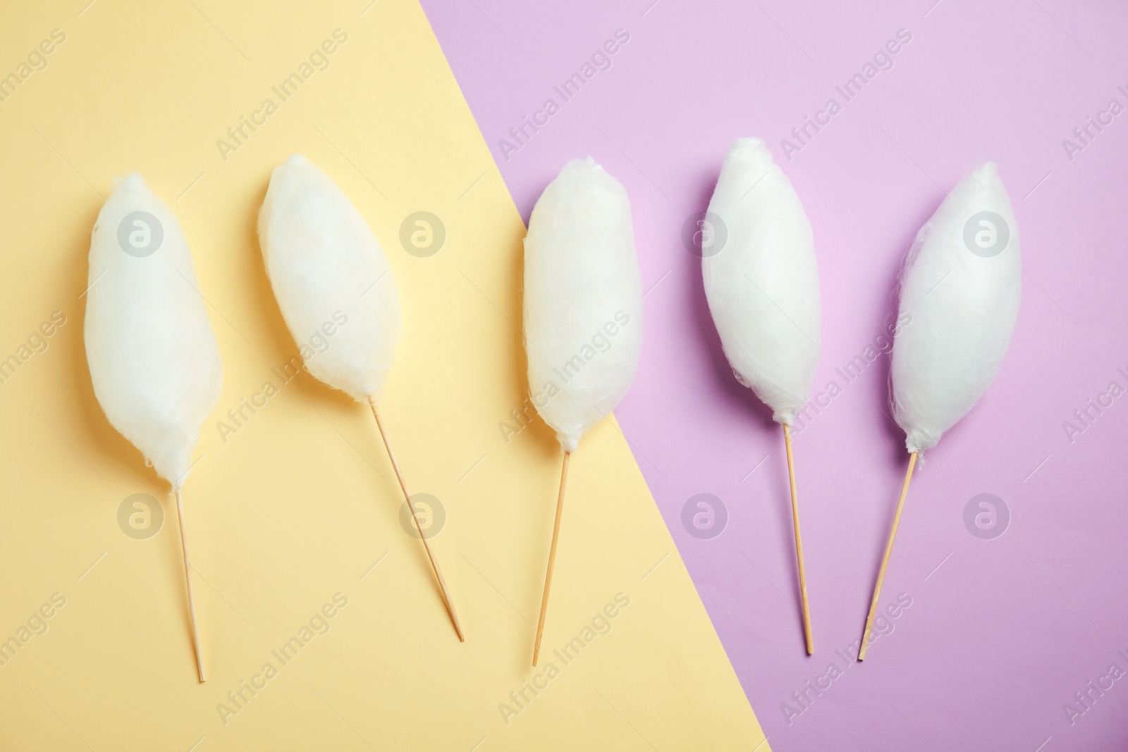 Photo of Sticks with yummy cotton candy on color background, top view