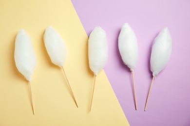 Photo of Sticks with yummy cotton candy on color background, top view